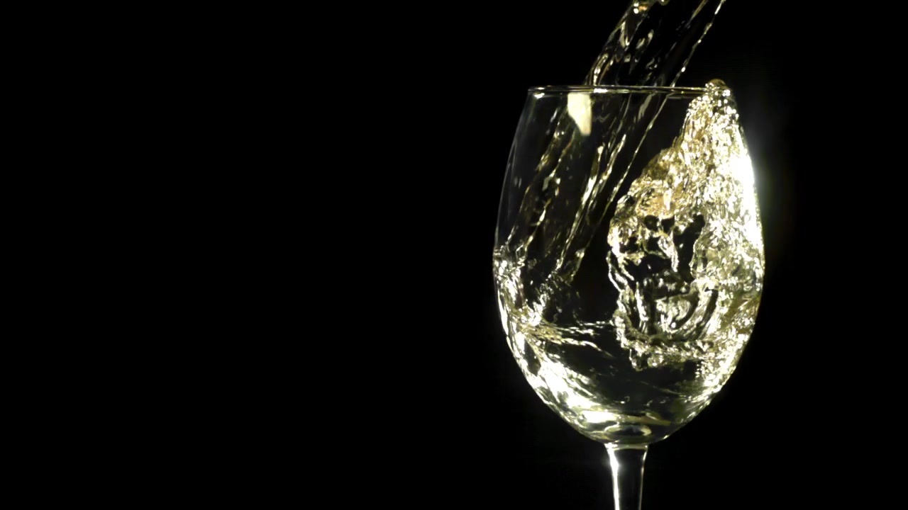 Vino bianco che si versa in un bicchiere al rallentatore su sfondo nero