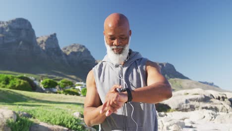 hombre afroamericano de alto nivel haciendo ejercicio usando un reloj inteligente escuchando música