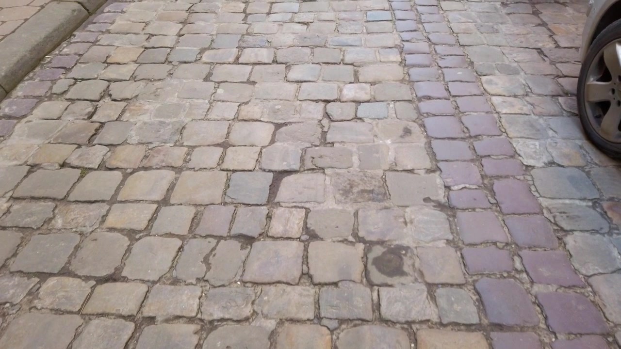 Old street of paving stone and parked cars.