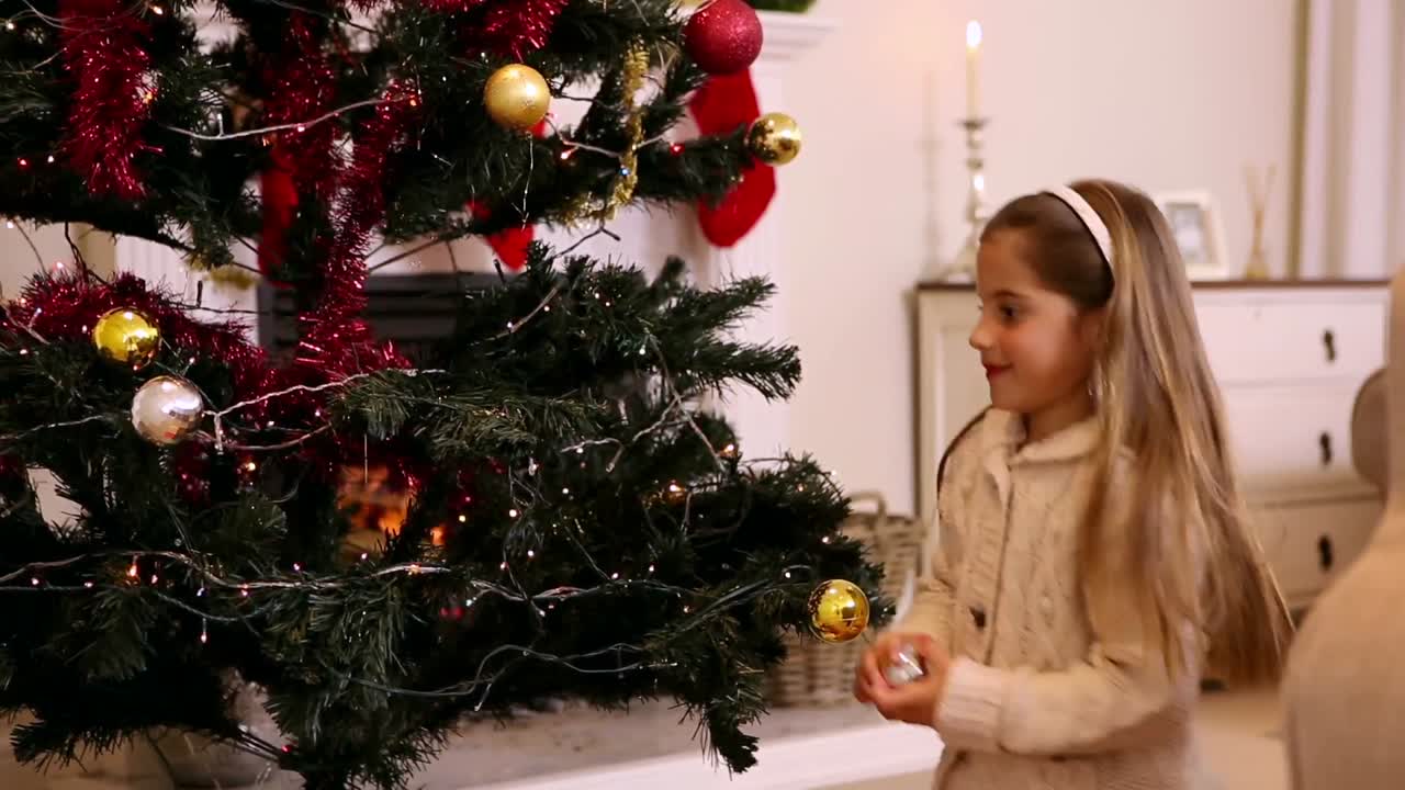 Little girl hanging decorations on christmas tree
