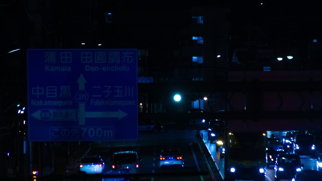 Timelapse notturno del traffico in una strada di Tokyo, in campo lungo.