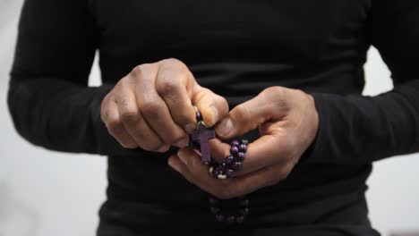 man praying to god with hands held tightly together with rosary beads stock footage