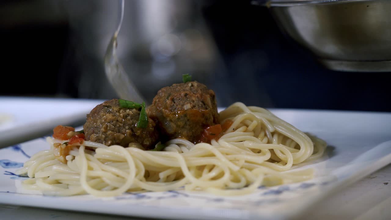 Aggiunta di polpette al piatto di spaghetti. Preparazione degli ingredienti per fare polpette vegane Beyond con spaghetti e ragù di carne.