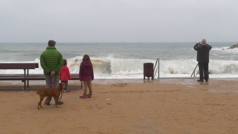 Menschen-Von-Hinten-Beobachten-Den-Sturm-Und-Die-Wellen,-Die-Am-Strand-Krachen