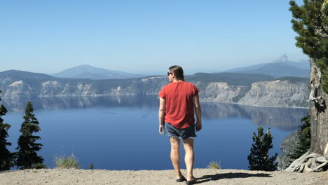 Mujer-De-Pie-En-El-Borde-Del-Lago-Del-Cráter-Contemplando-El-Agua-Y-Las-Montañas