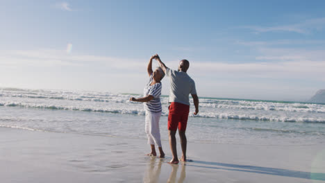 una pareja de ancianos afroamericanos bailando en la playa.