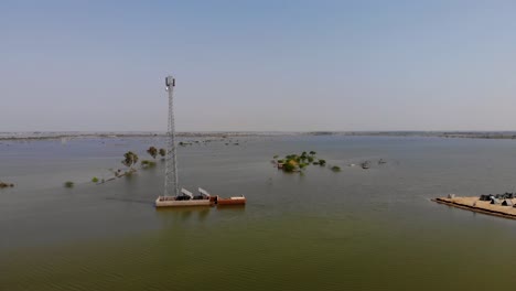 Disparo-De-Paralaje-Aéreo-Alrededor-De-La-Torre-De-Telefonía-Celular-Rodeada-De-Inundaciones-En-Jacobabad,-Pakistán