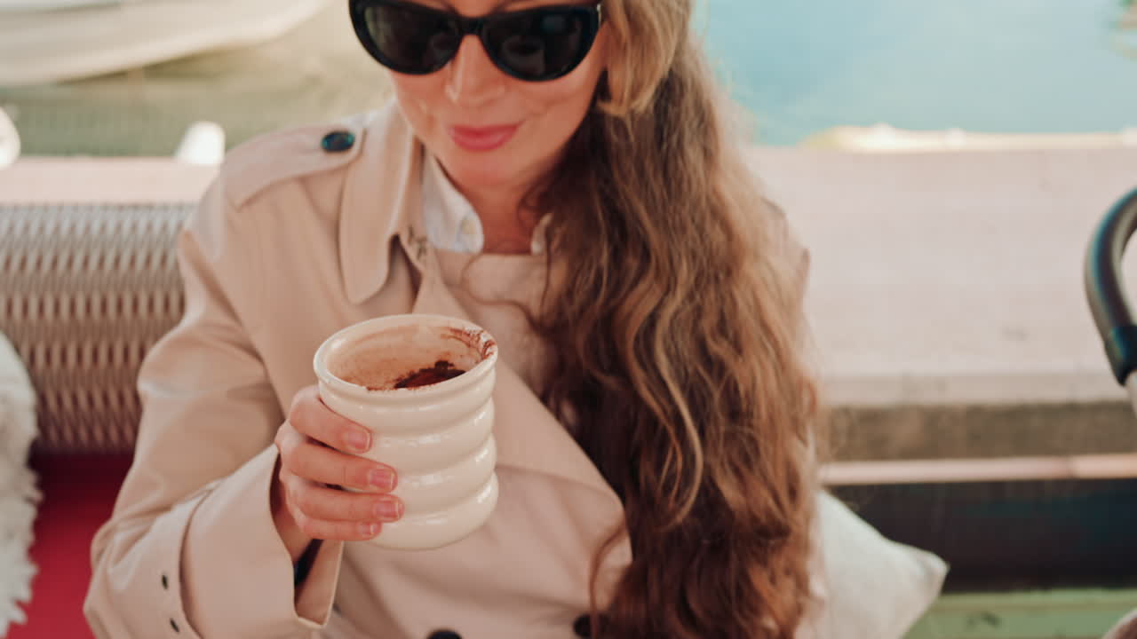 Woman's hand holding a cup of hot chocolate, with cocoa powder visible on top