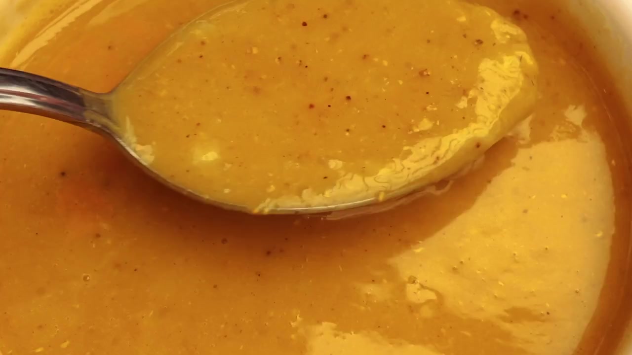 Primo piano di un cucchiaio che mescola una zuppa gialla densa