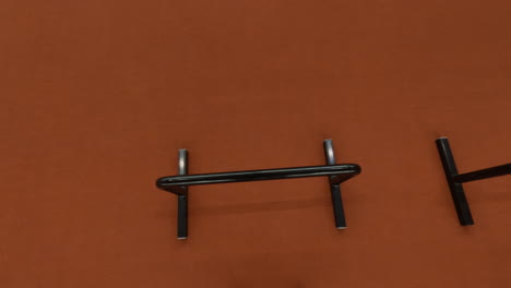hands gripping a pull-up bar against a textured orange wall