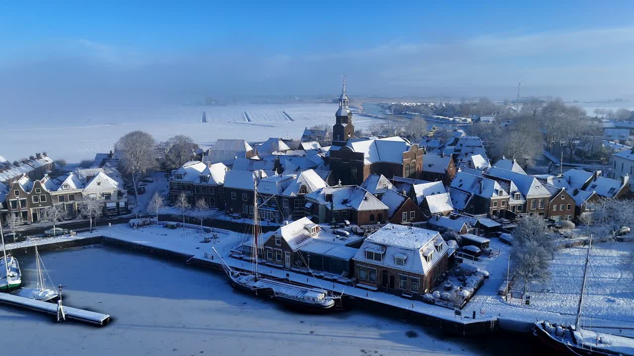 Blokzijl, Overijssel, Holanda, coberta de neve. Afastamento da igreja sobre o porto com barcos