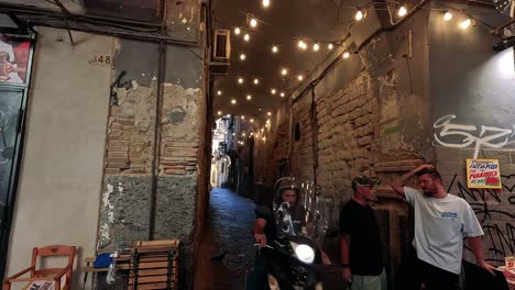 people and lights in a narrow, graffiti-filled alley