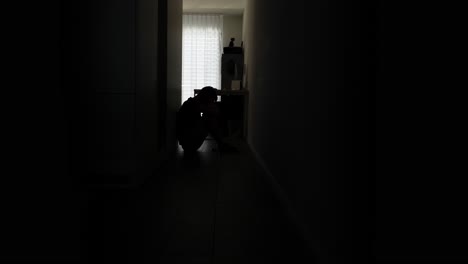 hopeless and depressed man sitting on end of hallway in his hotel room