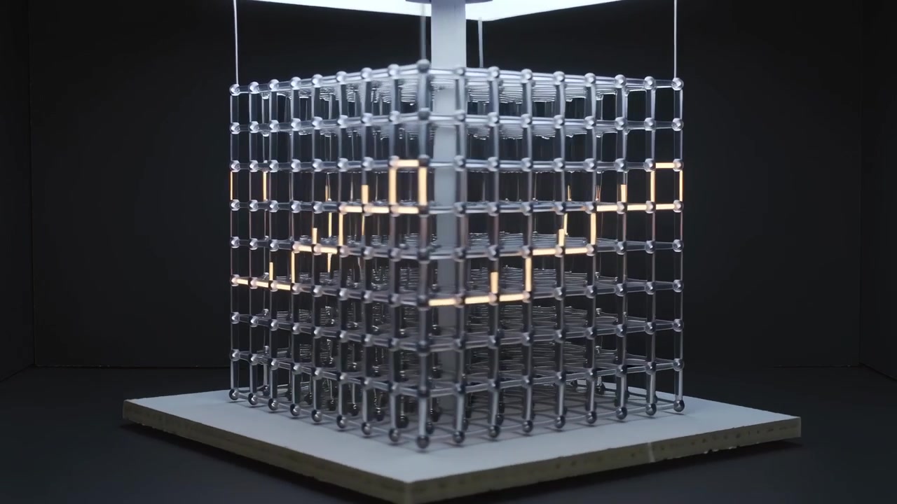 Sequenza luminosa che avvia un cubo modulare con strisce LED calde in movimento, creando un motivo a spirale in una galleria