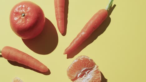 video of carrots and tangerines with copy space over yellow background