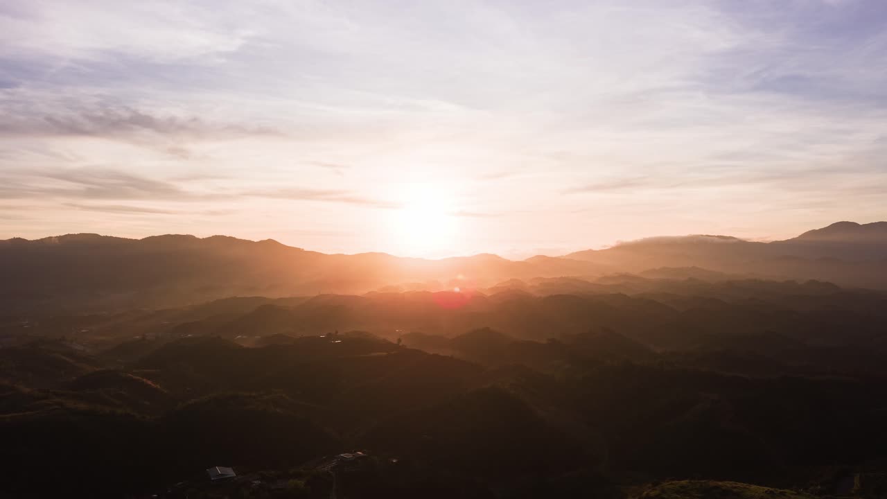 Las vistas de Lam Dong, Vietnam, muestran colinas y campos verdes. Carreteras sinuosas atraviesan el paisaje durante el amanecer, creando sombras y luces en la tierra.