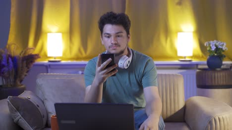 el hombre que envía mensajes de texto en el teléfono en casa por la noche está decepcionado.