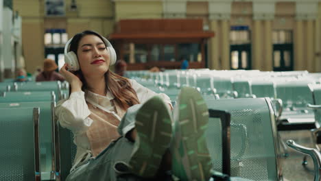 woman relaxing at train station with headphones