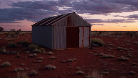 isolated corrugated iron shed in the red desert at sunset