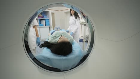 female patient is undergoing ct or mri scan under supervision of a radiologist in modern medical clinic. patient lying on a ct or mri scan bed, moving inside the machine.