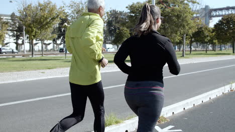 couple of mature runners jogging down street