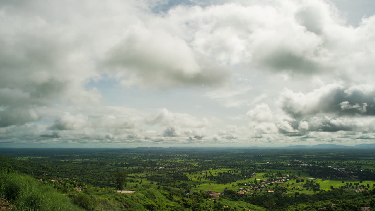 Nuvole soffici che scorrono su rigogliose risaie verdi durante la stagione delle piogge nelle pianure della Cambogia, Sud-est asiatico.