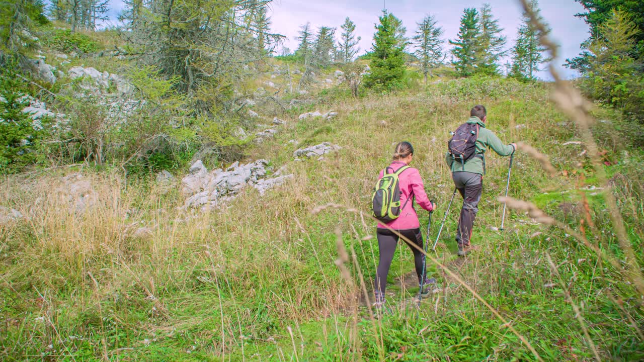 Active caucasian couple hike mountain with backpacks, enjoy adventure