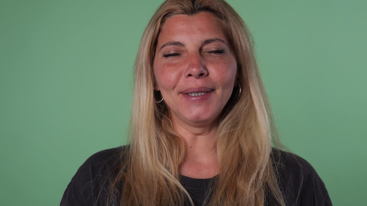 Volto di una donna adulta bionda che sbadiglia su sfondo verde.