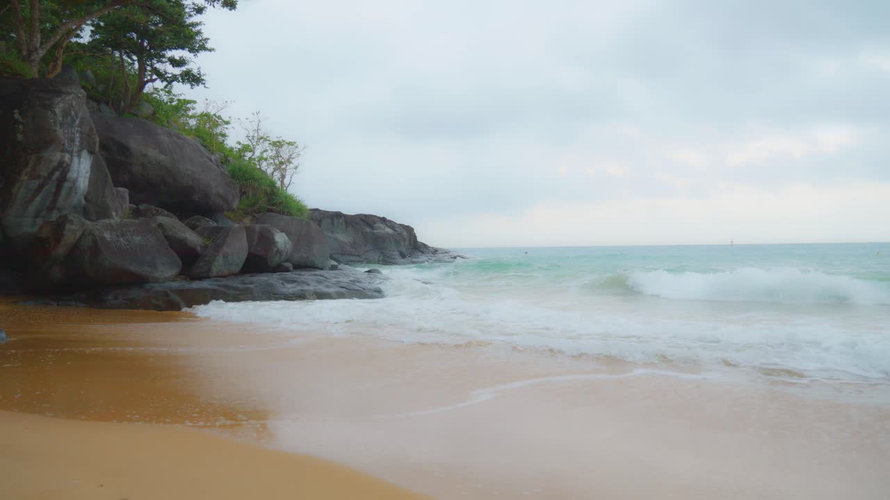 Pemandangan memesona ombak laut yang pecah di bebatuan dan pantai berpasir Pulau Con Dao