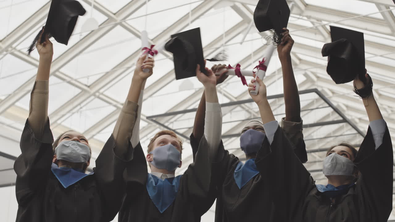 Group of Four Multiethnic Happy Students with Diplomas