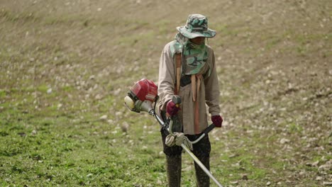 a person operating a string trimmer in a field