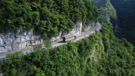 drone is following a truck on the road driving through breathtaking forests and canyons, high altitude, and winding road, captured at hebei province, china