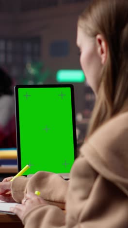 vertical video young female student studies for her upcoming exams with green screen