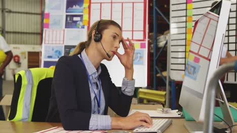 Young-woman-working-at-a-desk-in-a-warehouse-4k