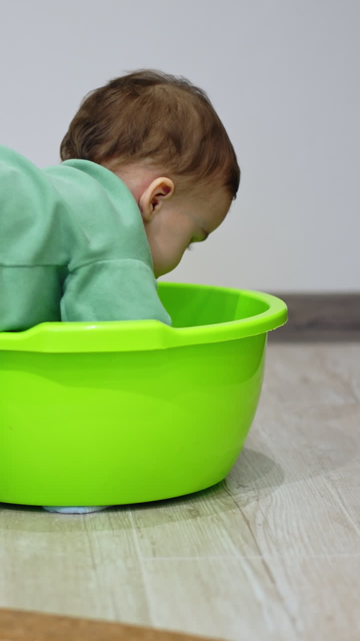 Sweet little kid sits at the washbowl. Lovely child in sport suit climbs inside the tub. Vertical video
