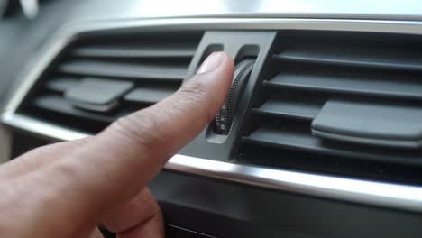 hand adjusting air vent in car interior