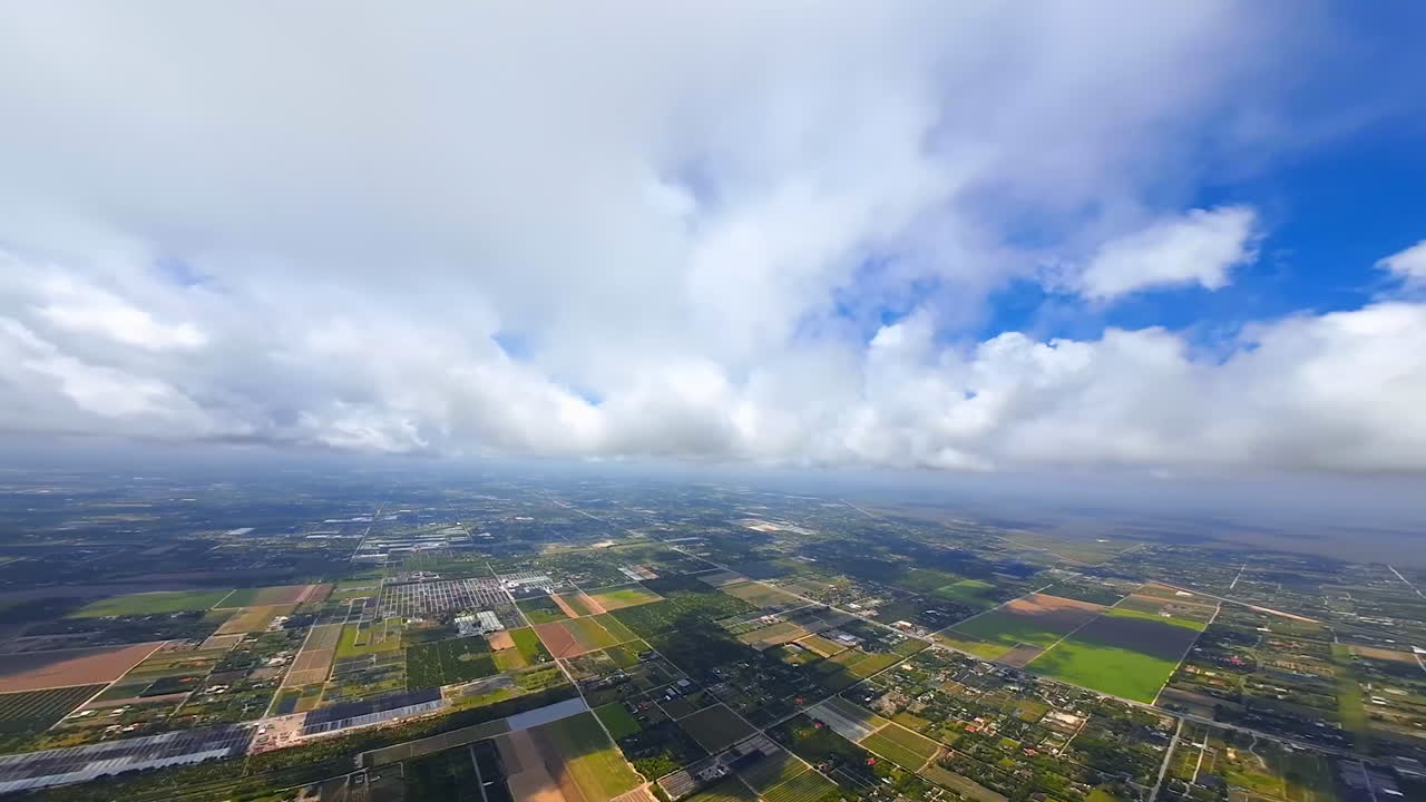 Panning footage of the vast territory divided on the diverse rectangular areas. PFV drone footage above the rural land with inhabited zones and farm lands.