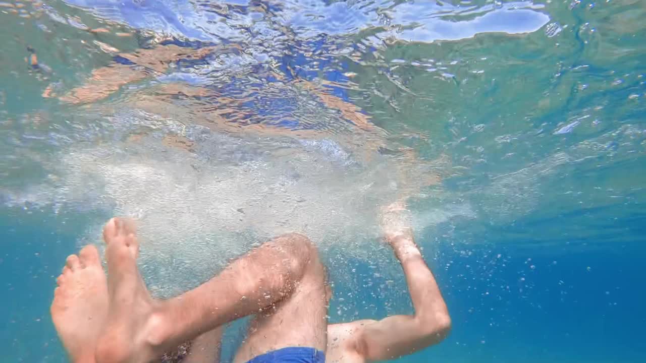 Man in swimming goggles rotating under the water, Aegean sea. Slow motion, underwater shooting. Greece
