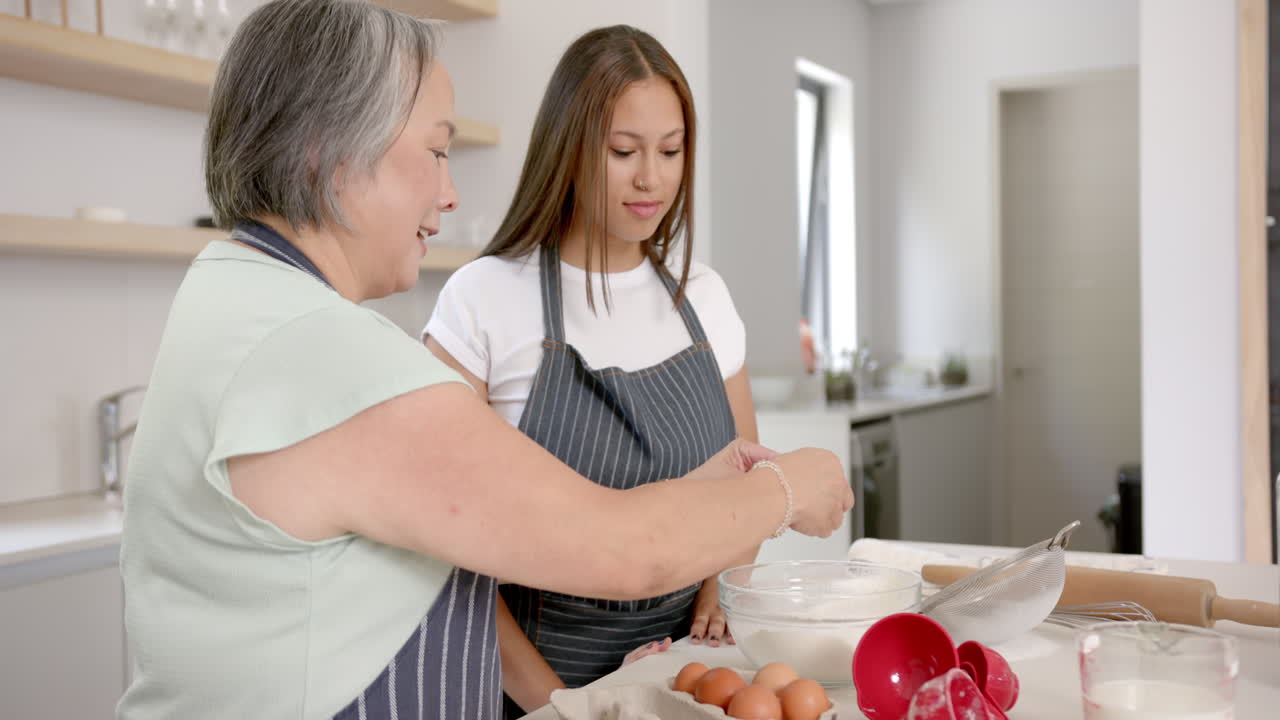 Preparing ingredients, asian grandmother and granddaughter baking together in kitchen