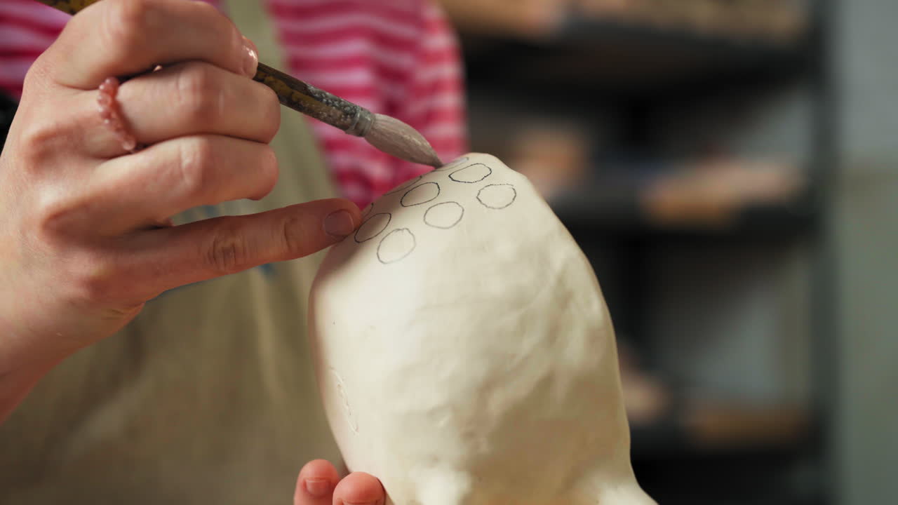 Female Hand Decorating Clay Mug Using Paintbrush. Pottery Design. closeup shot