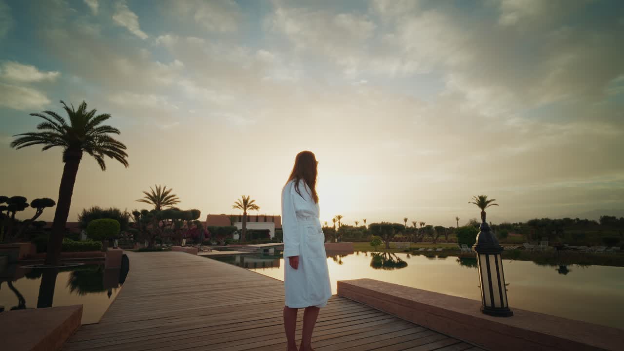 Young girl with a bath rope standing outside the Fairmont Royal Palm resort enjoying the beautiful sunrise.
