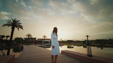 young girl with a bath rope standing outside the fairmont royal palm resort enjoying the beautiful sunrise.