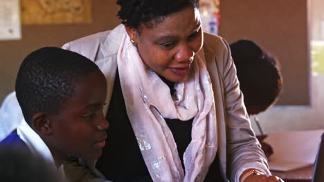 Teacher-helping-schoolboy-with-laptop-in-a-lesson-at-a-township-school-4k