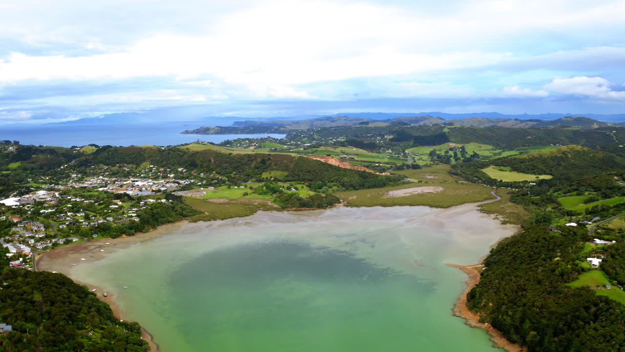 Aerial View of a Coastal Inlet and Town surrounded by Green Hills