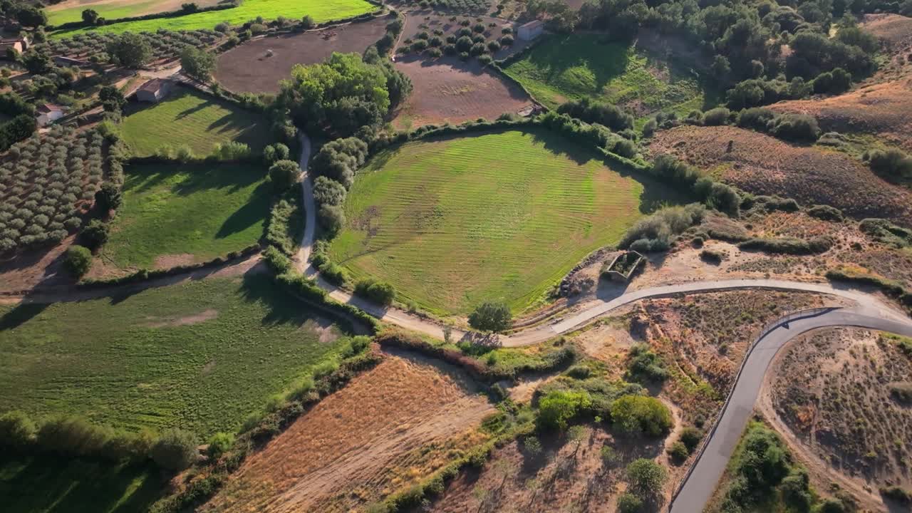 High quality drone filming of a rural system of plots in the countryside where they appear in different shapes, there are crops, others mowed and some green, we see dirt roads that connect them.