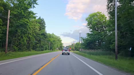 a peaceful drive down a scenic, tree-lined road under a partly cloudy sky