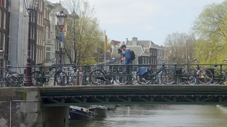 Fotografo uomo con macchina fotografica analogica ad Amsterdam - campo lungo.
