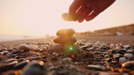 hand puts stones in the pyramid the sun's rays shine through his fingers