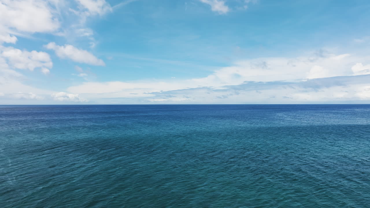 Smooth aerial dolly over calm peaceful ocean water with therapeutic idyllic clouds out to horizon