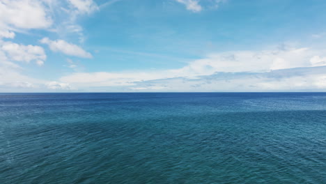 smooth aerial dolly over calm peaceful ocean water with therapeutic idyllic clouds out to horizon